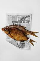 Smoked gutted breams with labels on tails on newspaper on white background photo