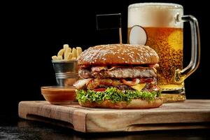 Hamburger with two patties, bacon, cheese, caramelized onions, tomatoes served with light beer, fries and aioli photo