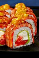 Closeup of uramaki roll with cream cheese, tobiko, avocado, seared salmon and mango photo
