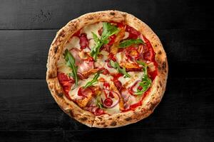 Pizza with pelati sauce, cheese, sausages, bacon, sous vide chicken, onion, chili pepper photo