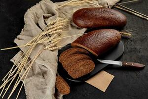 Whole and sliced rye bread with ears of wheat and burlap photo