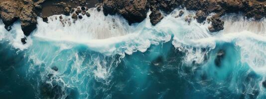 Top view of the ocean and foamy waves crashing against the red rocks photo