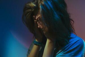 Deprimido adolescente niña cubierto su cara con su manos experimentando mental sufrimiento. foto