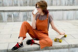 Skater young woman resting drinking coffee outdoors. photo