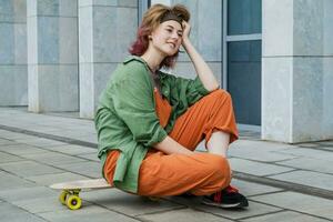 Skater teen girl resting after riding plastic mini skateboard. photo