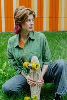 Active sporty teen skater girl with plastic skateboard outdoors. photo