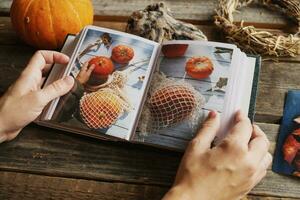 Hands browsing photo album with autumn printed photos.