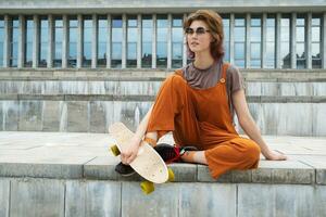 Skater girl resting after skateboarding in city. photo