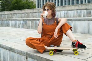 Skater teen girl resting drinking coffee outdoors. photo