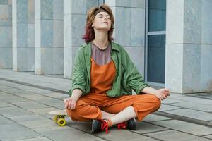 adolescente mental salud concepto. patinador niña sentado en patineta en yoga pose. foto