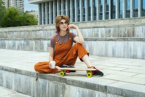 Female skateboarder relaxing holding white coffee container in her hand. photo