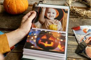 Halloween printed photos in picture album. Female hand holding photo album.