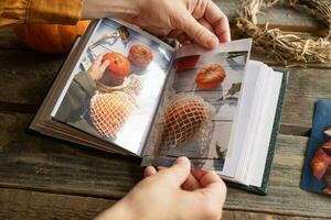 Hands put autumn printed photos in picture album.