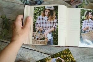 Female hand holds photo album with printed photos.