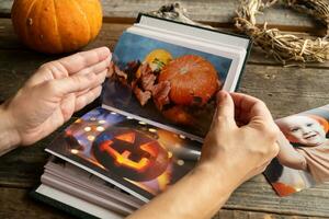 Halloween printed photos in picture album. Female hands hold photo album.