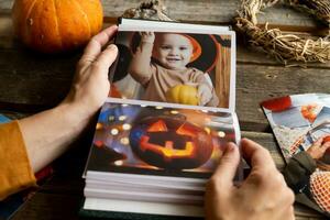 Halloween printed photos in picture album. Female hands browsing photo album.