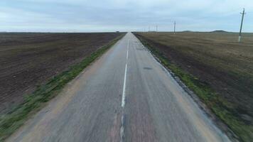 vôo frente e para cima sobre a asfalto direto estrada dentro campo. aéreo visualizar. video