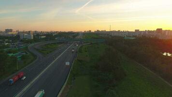 tráfico de carros en un autopista a soleado verano Mañana en el ciudad. urbano paisaje urbano volador adelante. aéreo vista. video