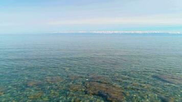 Low angle flying forward over the clean transparent lake. Shingle at the bottom. Boat view. video