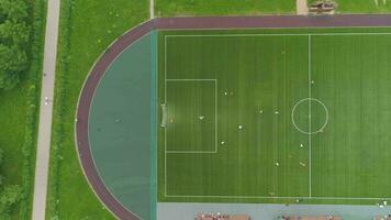 Flying over green soccer field to the right. Players playing football. Aerial vertical top view. video
