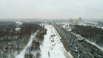 Straße der Verkehr von Autos auf ein Autobahn im schneebedeckt Winter. Antenne Sicht. fliegend rückwärts. video
