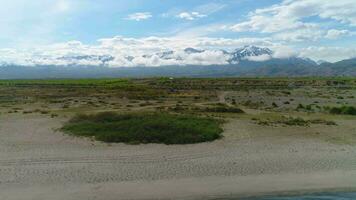 Minivan car is going on asphalt road. Green meadow, grey sky with clouds. Aerial view, drone flying forward. video