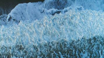 salpicando mar olas con noche ligero destello. aéreo vista. video