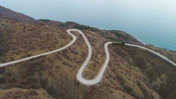 Serpentine road, green hills and sea. Aerial view. Flying backward. video
