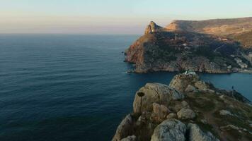 volador adelante terminado el rocas, colinas y mar apuntalar a amanecer. video