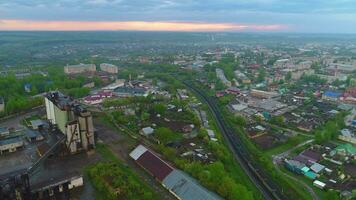 Flying forward over passing train in the city industrial district at sunset. Aerial view. video