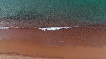 stänk hav vågor och rena vatten nära röd sandig strand. antenn se. video