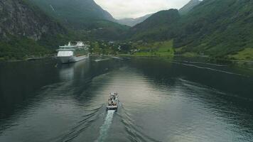 pequeño Embarcacion y grande crucero transatlántico en geiranger fiordo en verano día. Noruega. aéreo vista. zumbido órbitas alrededor video