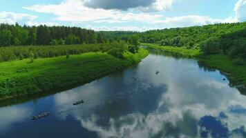 kayaks son yendo en azul río. verde prado y arboles aéreo vista. video