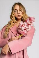 Seductive blonde woman in pink jacket posing in studio photo