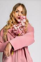 Seductive blonde woman in pink jacket posing in studio photo