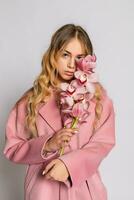 Seductive blonde woman in pink jacket posing in studio photo