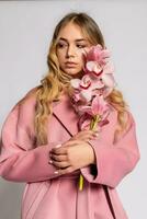 Seductive blonde woman in pink jacket posing in studio photo