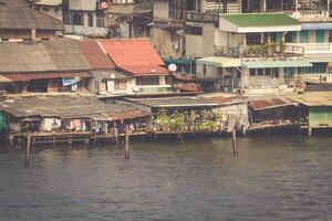 Wooden slums on stilts on the riverside of Chao Praya River in Bangkok, Thailand photo
