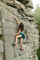 un niña sube un roca. mujer comprometido en extremo deporte. foto