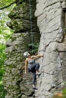 un niña sube un roca. mujer comprometido en extremo deporte. foto