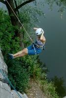 A girl climbs a rock. Woman engaged in extreme sport. photo