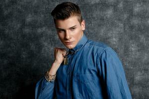 Man in denim shirt, arms on hips, gray background. photo