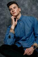 Man in denim shirt, arms on hips, gray background. photo