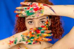 Close-up portrait of red curly haired woman Young cheerful soiled in paint. photo