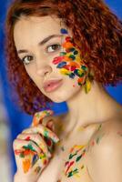 Close-up portrait of red curly haired woman Young cheerful soiled in paint. photo