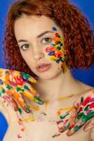 Close-up portrait of red curly haired woman Young cheerful soiled in paint. photo