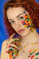 Close-up portrait of red curly haired woman Young cheerful soiled in paint. photo