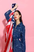 Portrait female athlete wrapped in American Flag against pink background photo