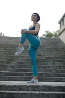 Full length of a sportswoman doing stretching exercise by a wall outdoors photo