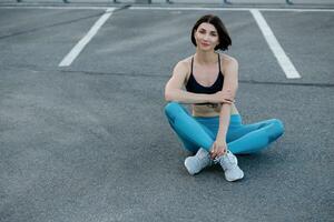 Fit young woman sitting outdoors after workout session in morning. photo